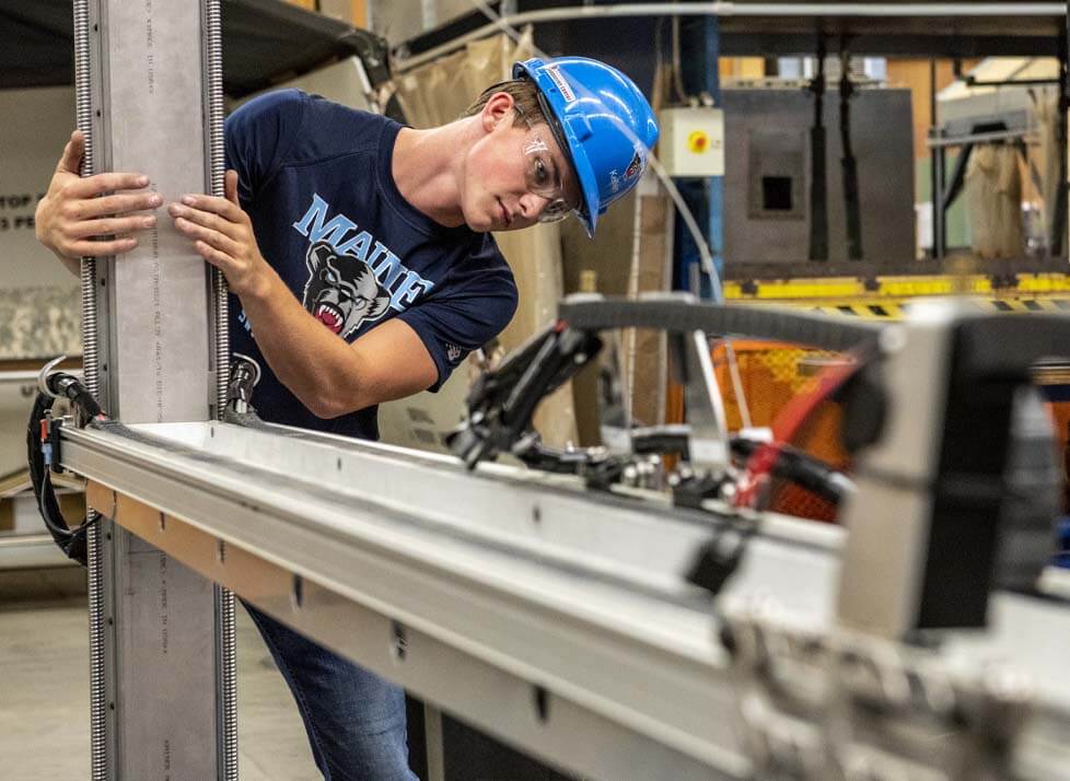 A photo of a student in a lab wearing a hard hat