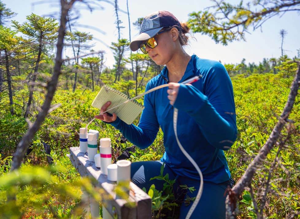 A photo of a student in a bog with research equipment