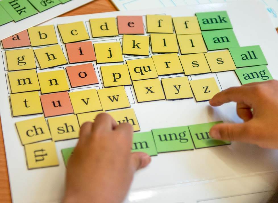 A photo of hands and letter tiles