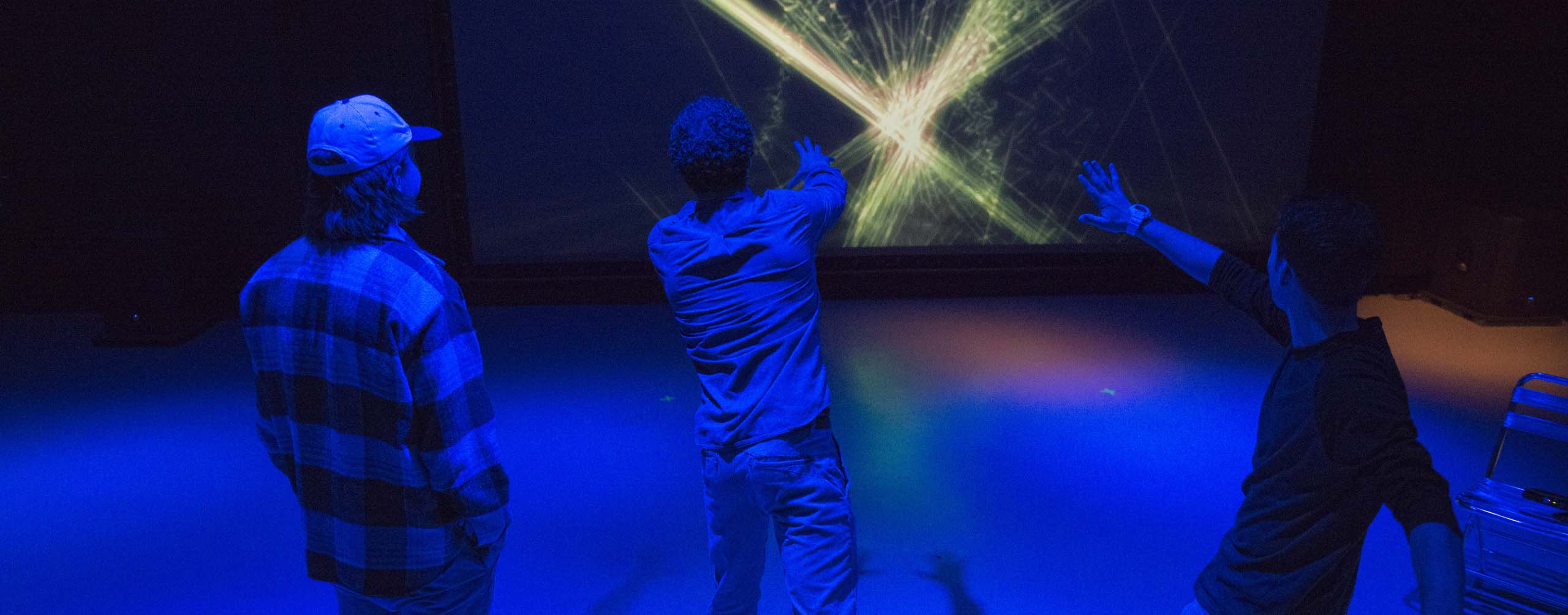 A photo of three people in front of a large screen