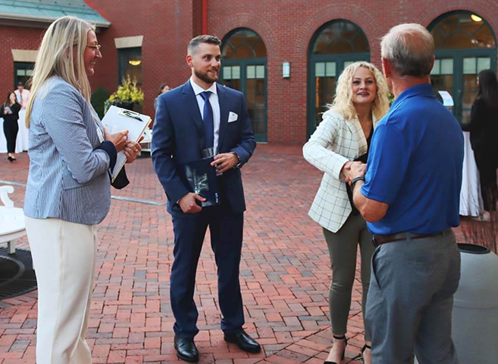A photo of people standing in a brick courtyard wearing business apparel