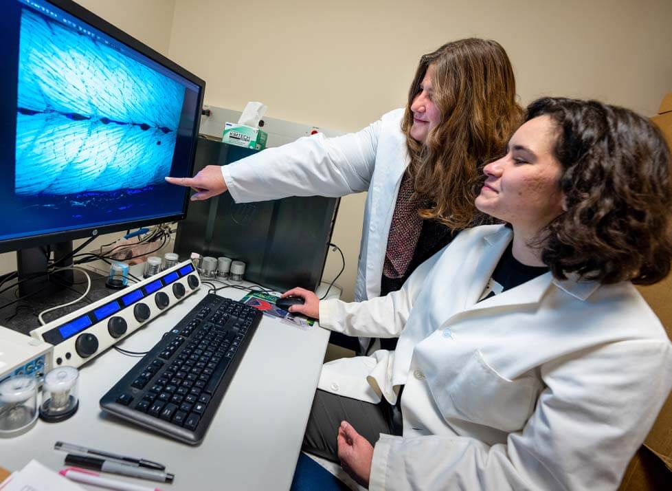 A photo of a student and professor in a lab, looking at a computer