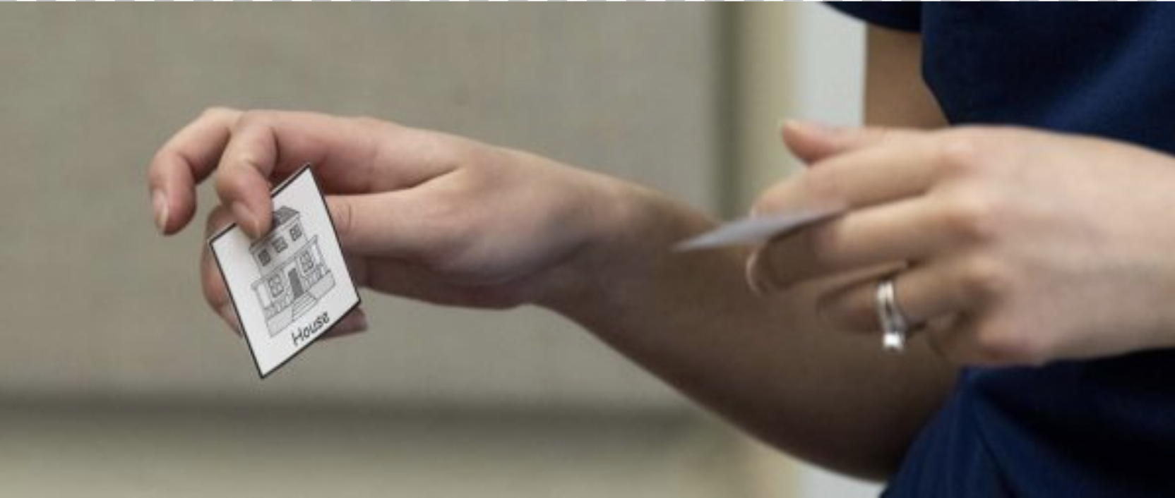A photo of hands holding a flash card with a house on it