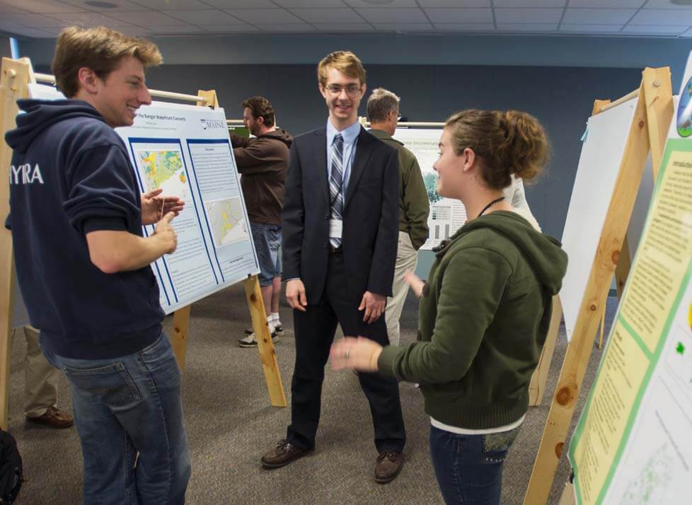 A photo of three people standing next to posters