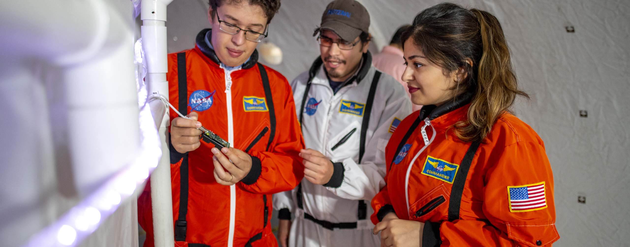 A photo of three people in jumpsuits in a lunar habitat