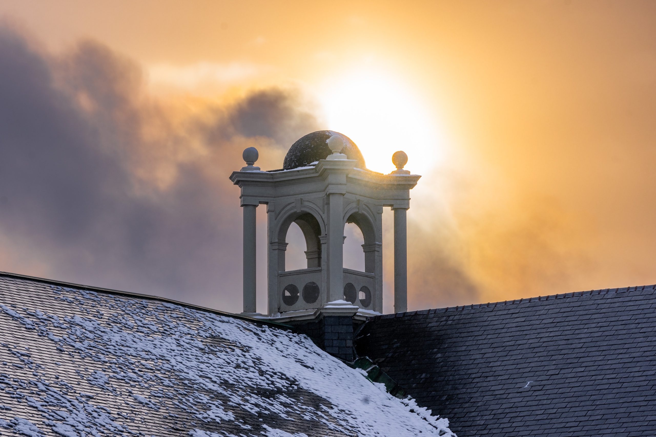 Alumni Hall in Winter with sunset coming down by the bell tower