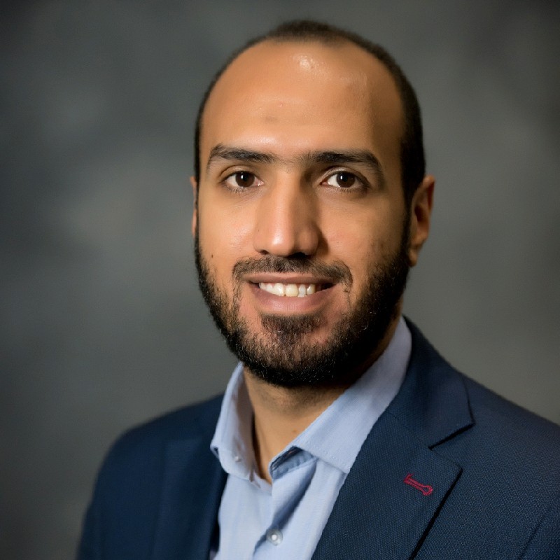 Hesham Mahmoud smiling and wearing a collared shirt and suit jacket