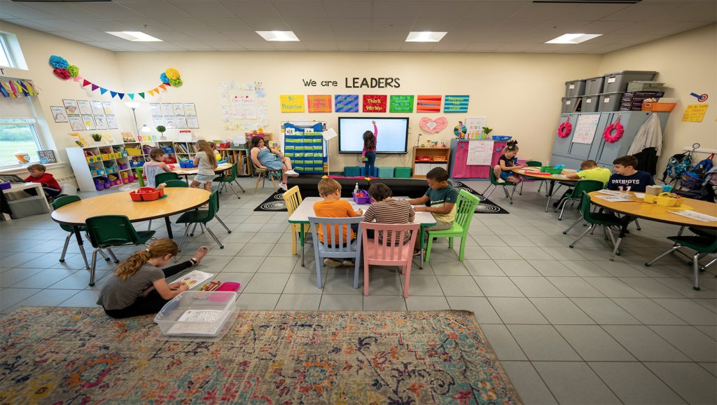 A photo of a children and a teacher in a classroom.