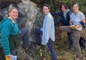 4 graduate students studying a rock