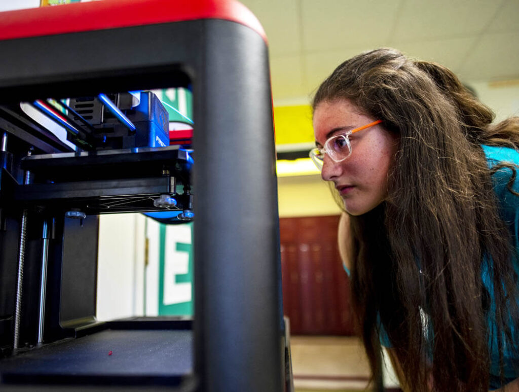 A woman looks at a 3D printer