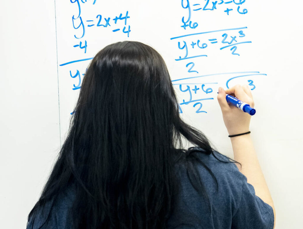 A woman writes on a dry erase board