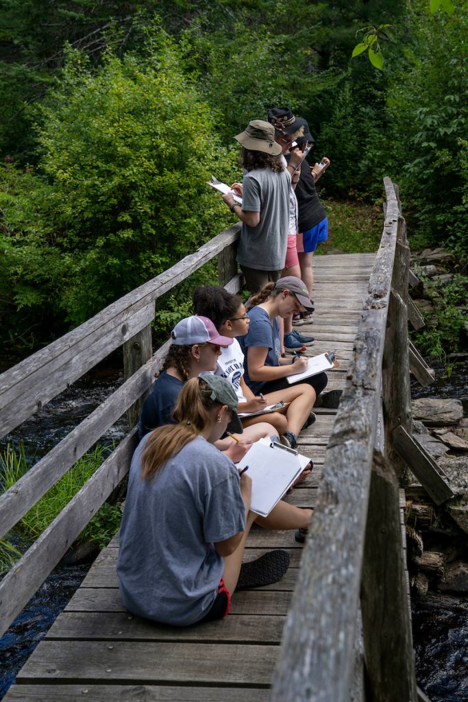 A photo of students taking notes on a bridge