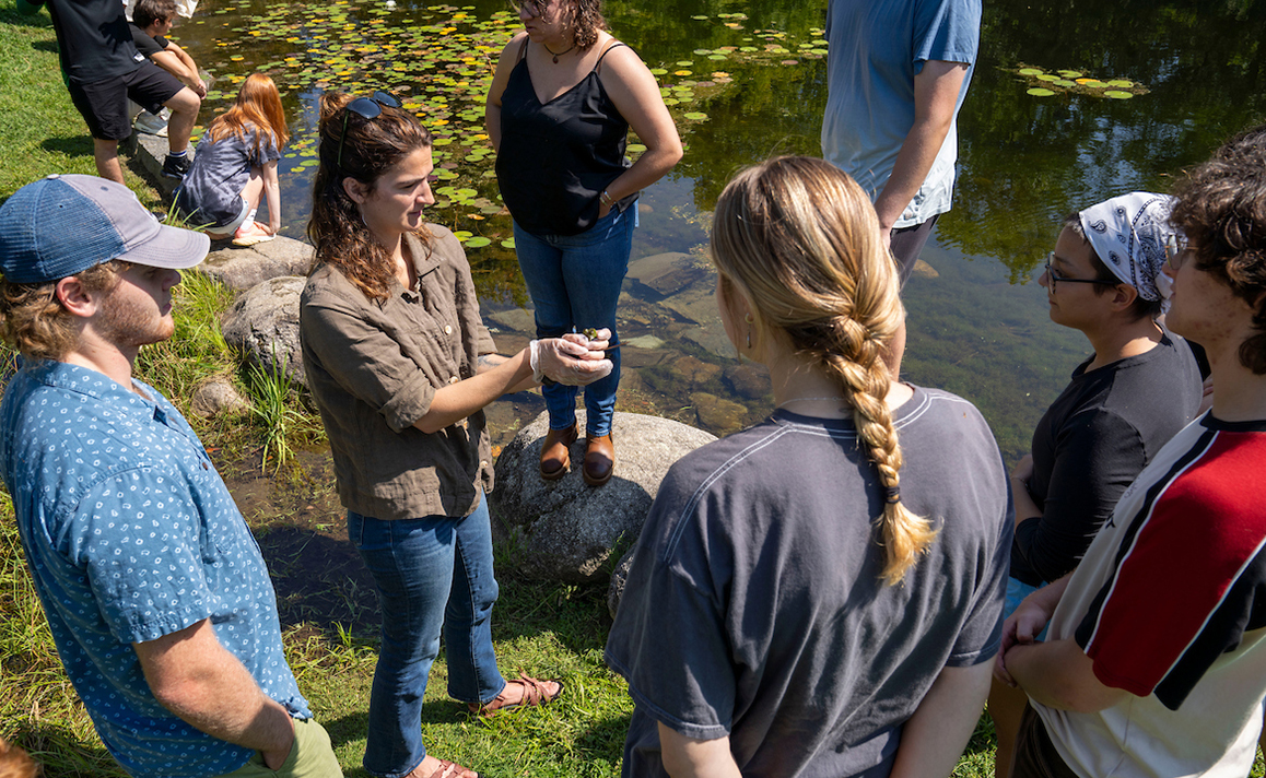 A photo of students surrounding a teacher with a frog