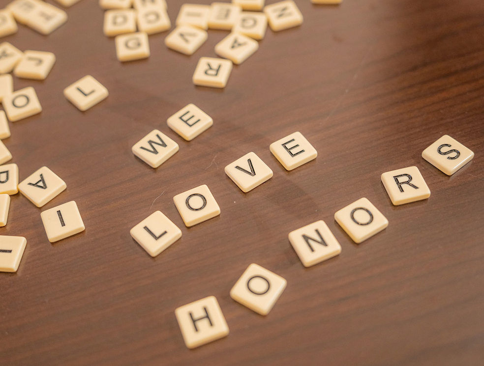 A photo of Scrabble tiles that read "We Love Honors"