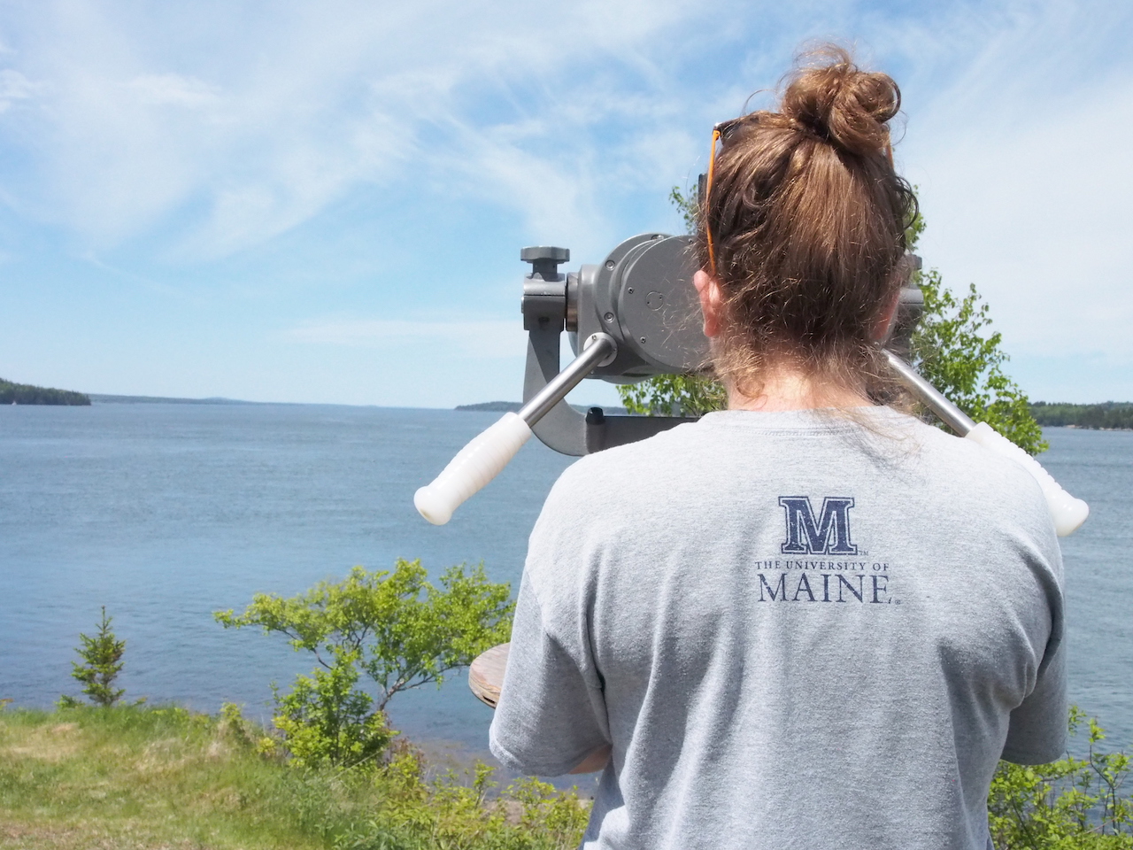 Emma Newcomb looking through telescope at ocean