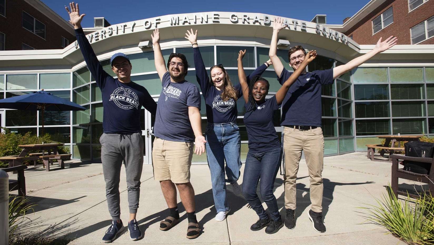 Five individuals pose in front of UMaine's Graduate School on a summer day