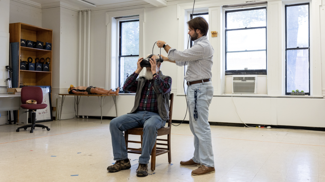 Image of Justin Brown assisting a visitor with a VR demonstration.