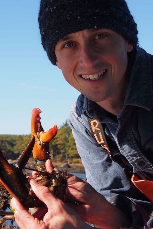 A portrait of Josh Stoll holding a lobster