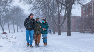 Students walking on campus mall in a winter snowfall
