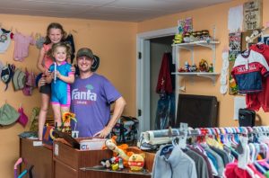 father and two daughters posing behind the counter at a thrift store