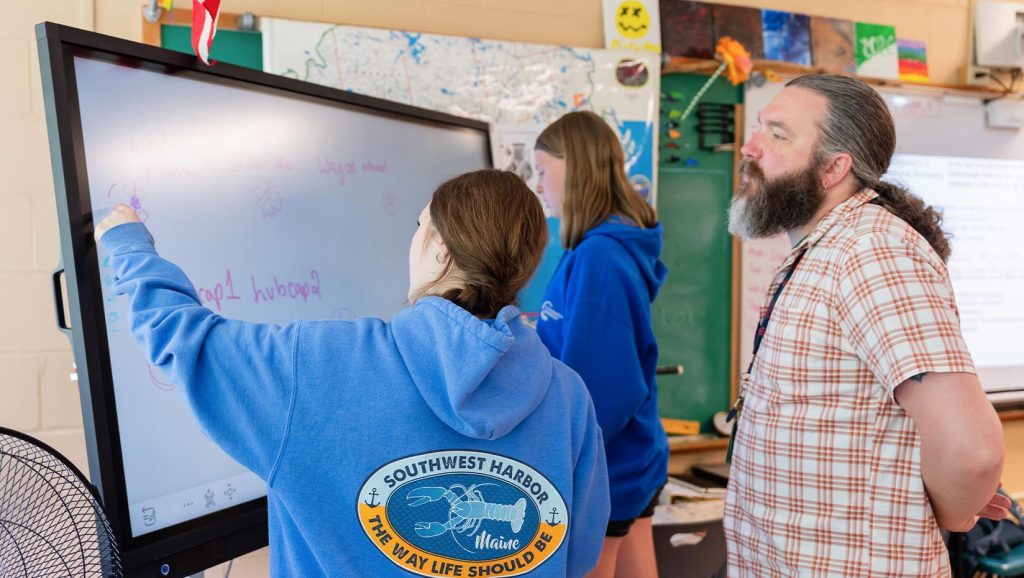 A photo of three people in a classroom.