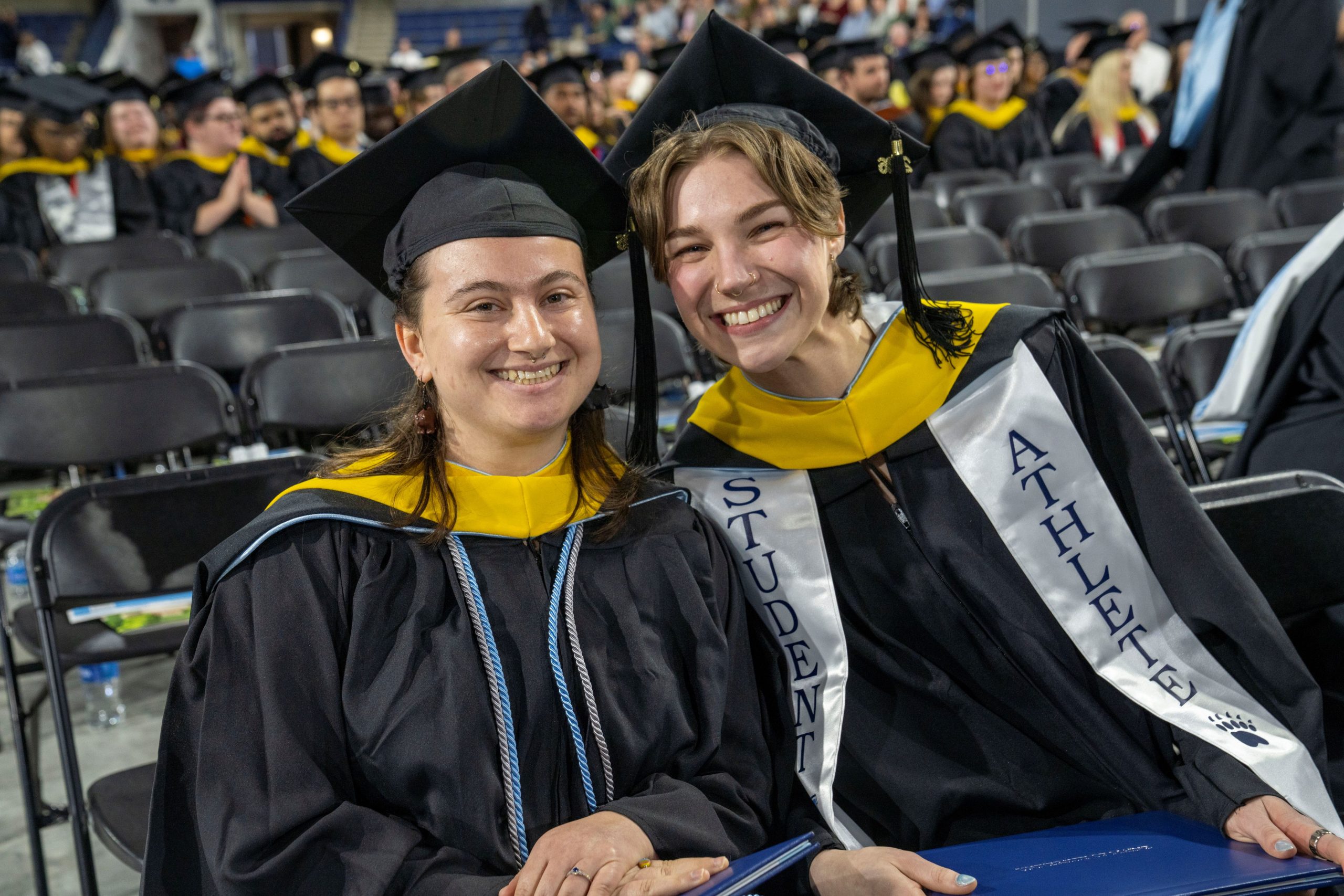 Two people at graduation holding diplomas