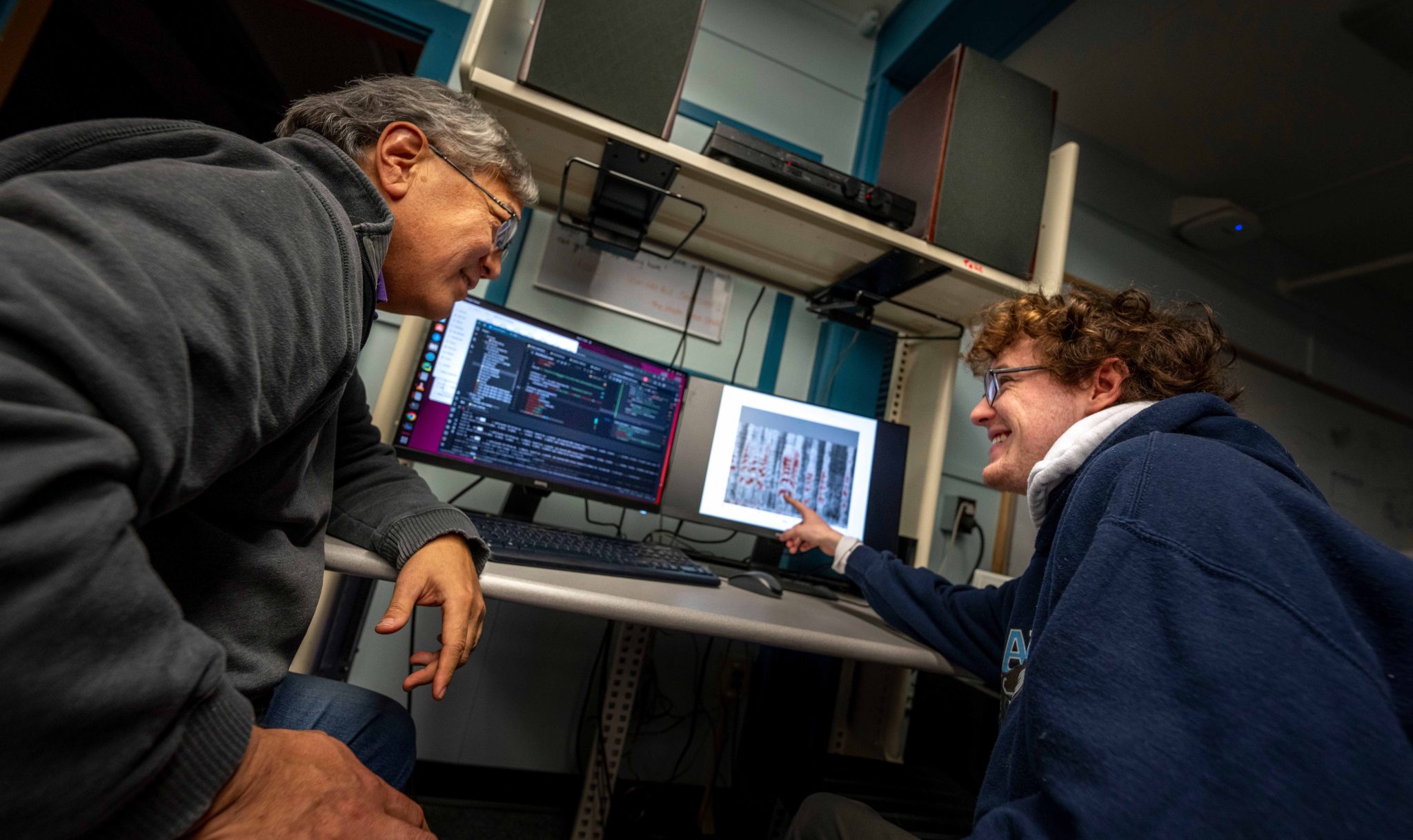 Student pointing at a computer and smiling