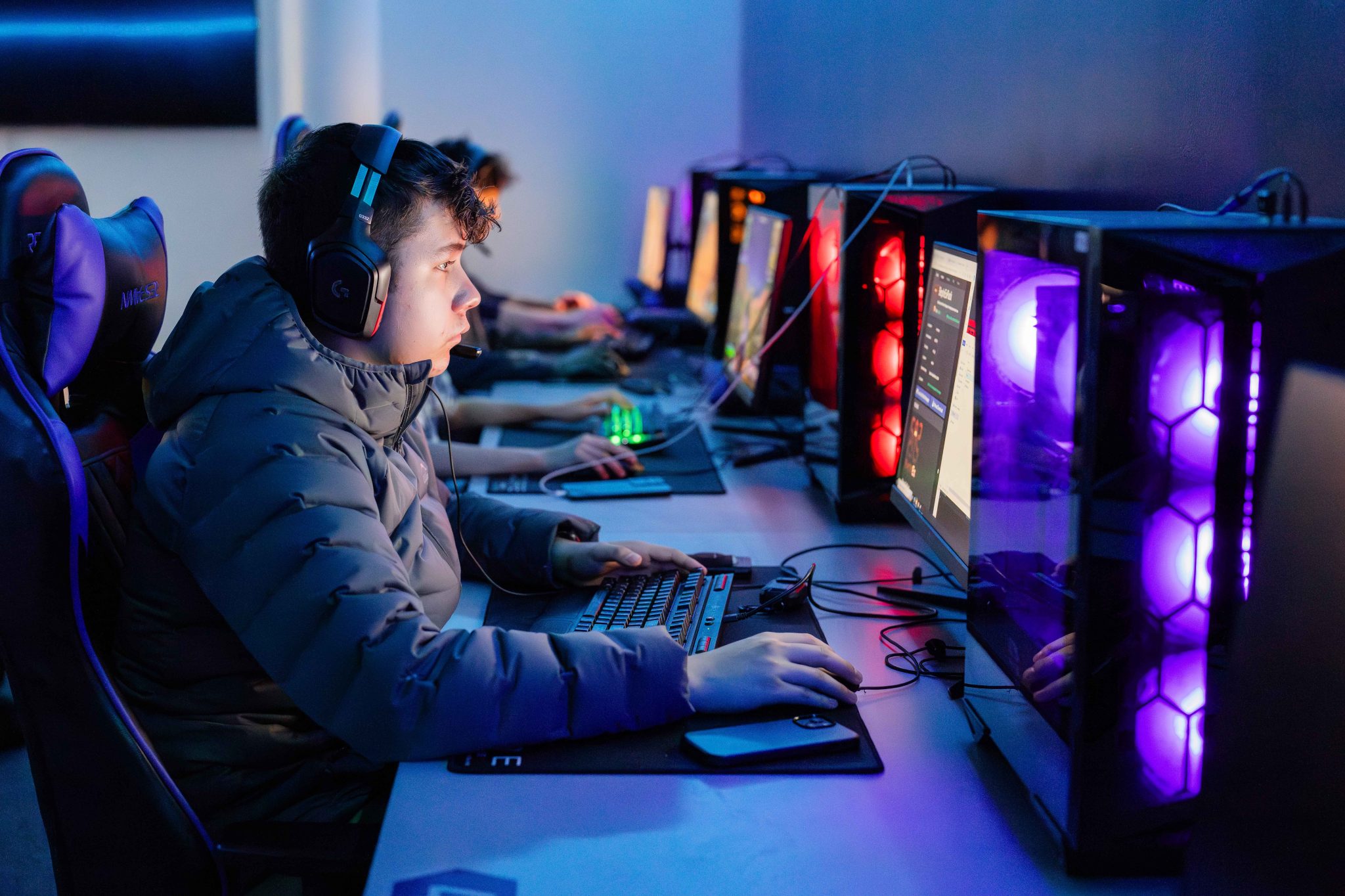 Student sitting in a gaming chair with headphones on, working on a gaming computer