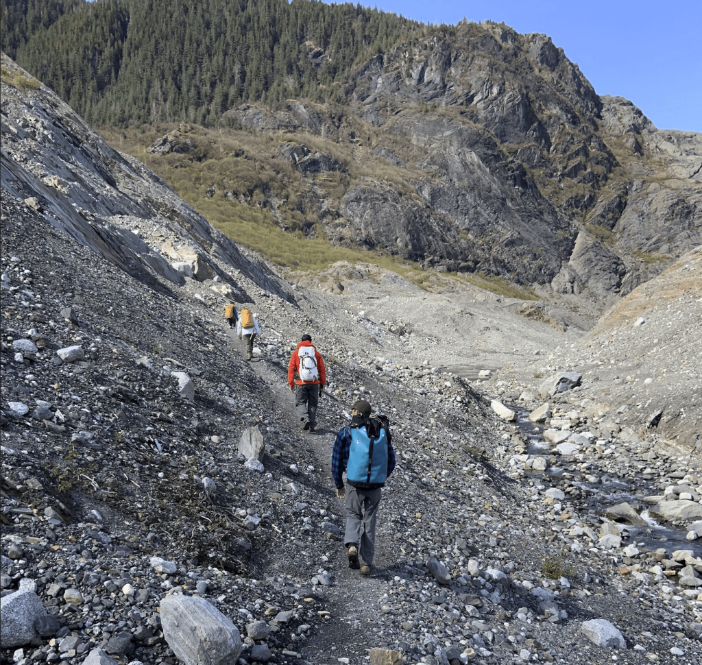 Students walking around rocky path at Mendenhall glacier.