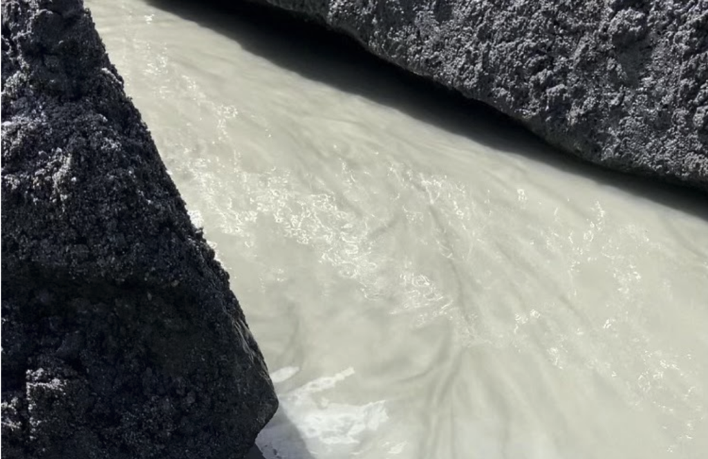 Cloudy water flowing between rock outcrops.