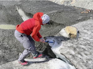 A student using an ice pick to chip away at a glacier.