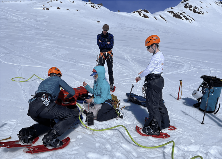 Students surrounding radar technology on a snowfield.