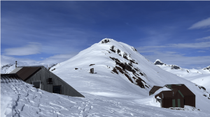 Houses buried in snow with a peak in the background at JIRP Camp 17 on Lemon Creek Glacier