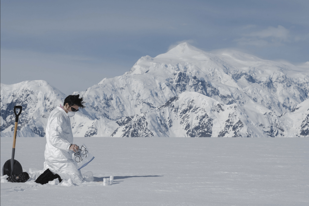 STudenting conducting tests on a snowfield in front of Mount Logan