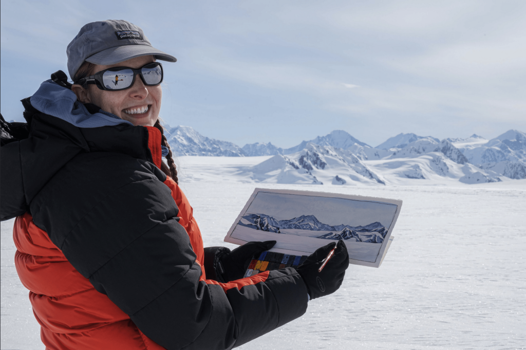 Claire Giordano showing her art of the mountainscape seen in the background