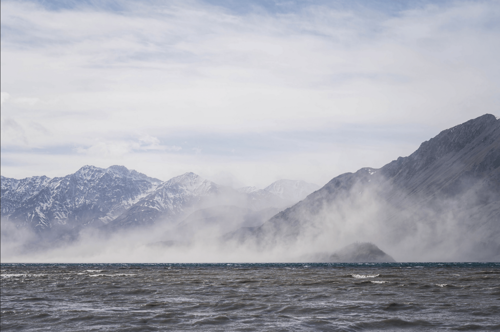 Steam rising off of lake with moutnains in the background