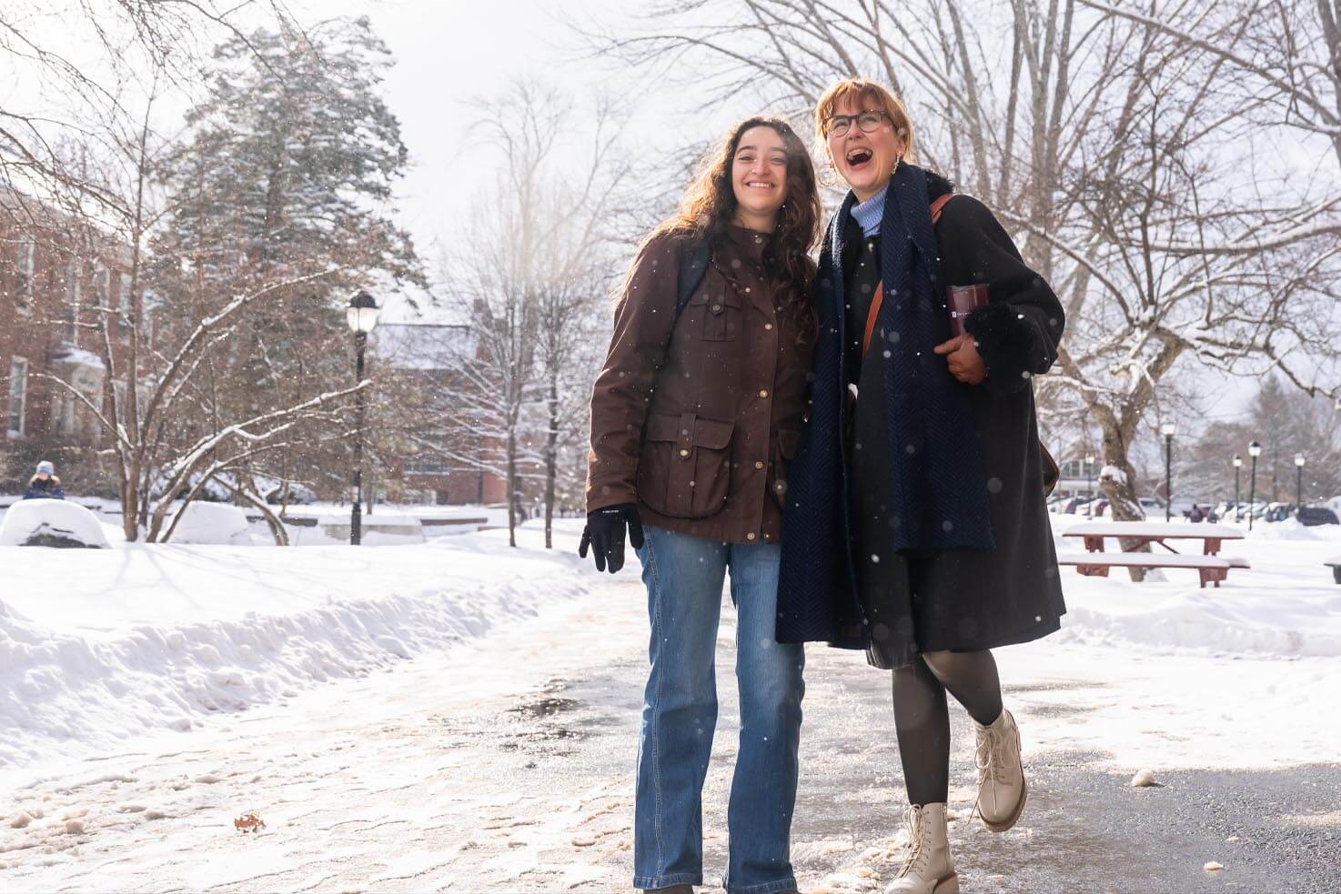 A photo of two people walking in the snow on UMaine's campus