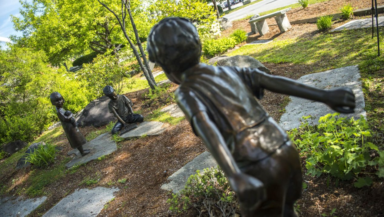 Statues of children playing in UMaine's rose garden