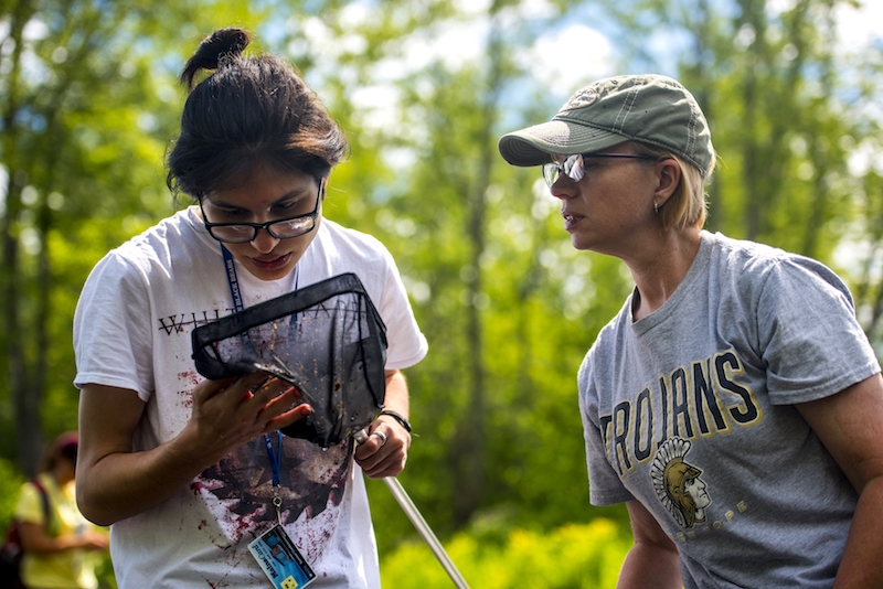 a SMART student and teacher look at macroinvertebrates in a D-shaped net