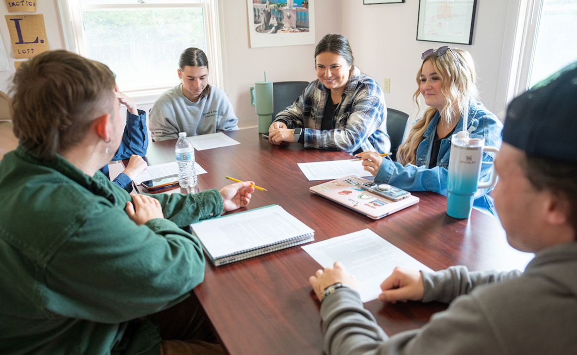 A photo of students discussing around a table