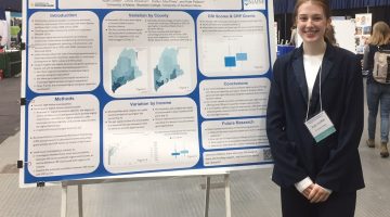Photo of student presenting poster at conference