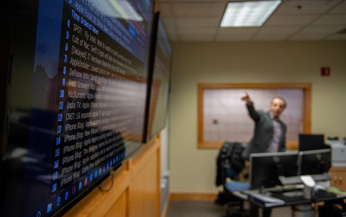 A photo of a teacher pointing to a computer screen