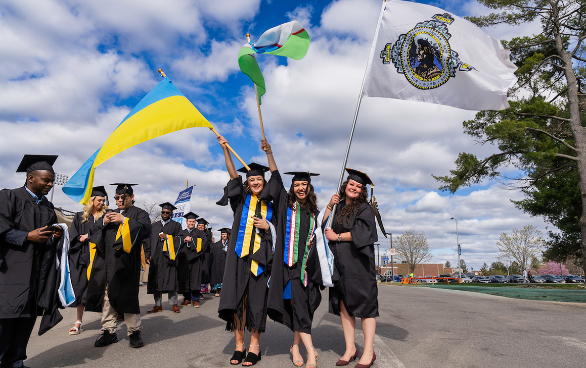 A photo of graduate students holding international flags