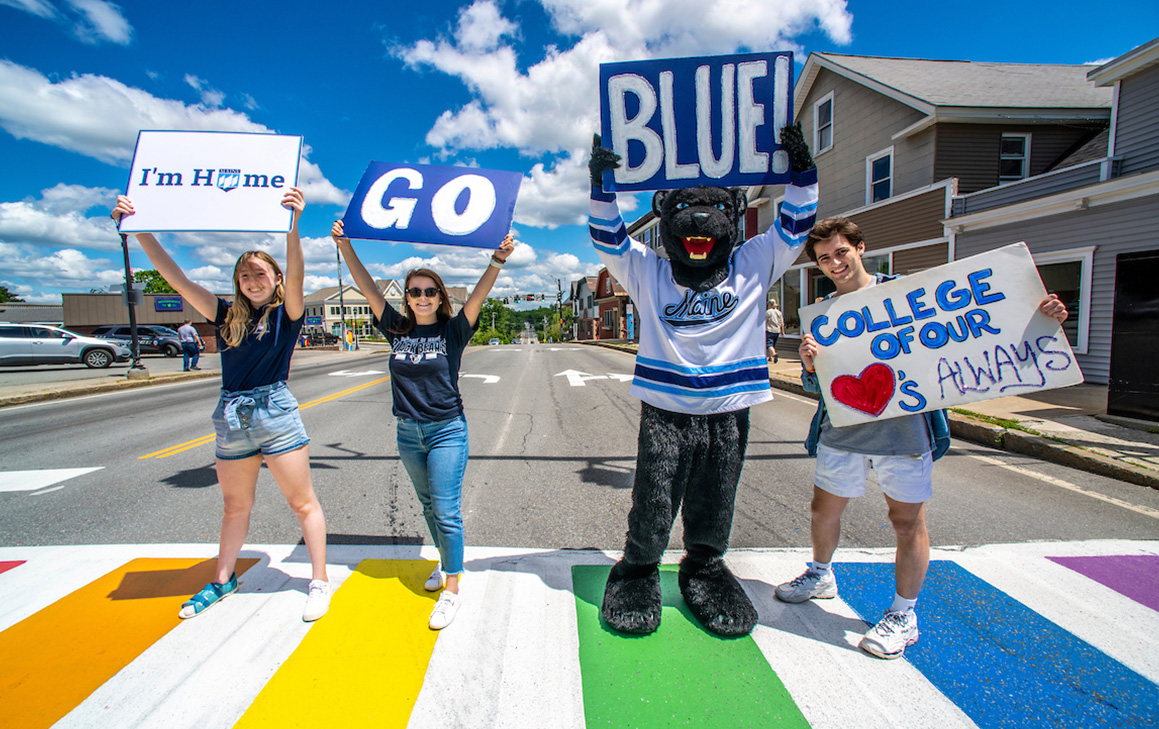 A photo of students and Bananas T. Bear holding up welcome signs