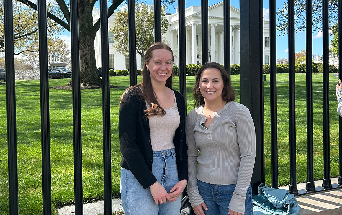 A photo of two graduate students standing in front of the White House