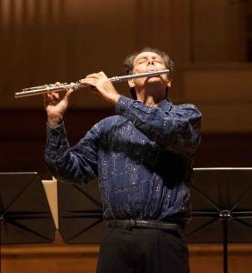 Robert Dick playing the flute on a concert stage