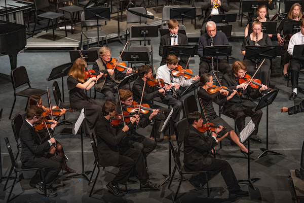 Members of the string section performing on stage at the Collins Center for the Arts