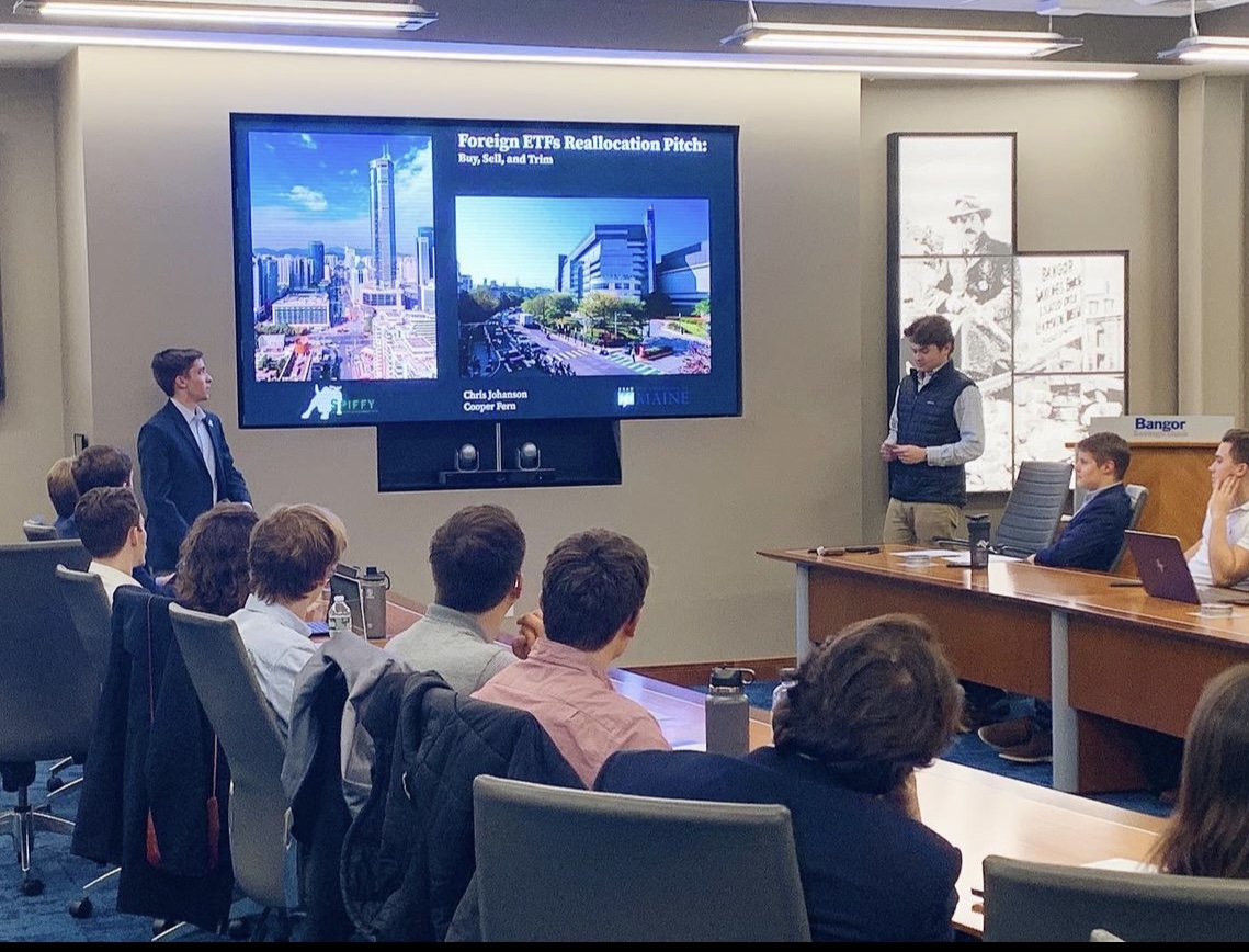 students sitting around a large monitor showing a powerpoint