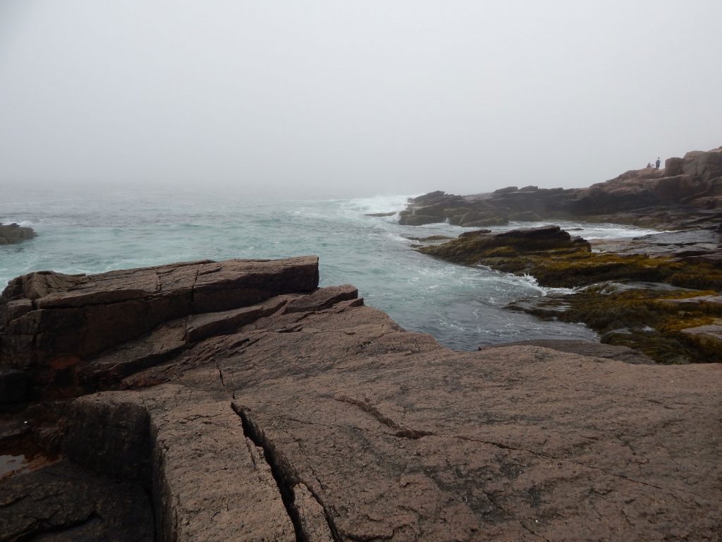 Photo of the ocean, along a rocky shore. Artist is Amanda Moline.