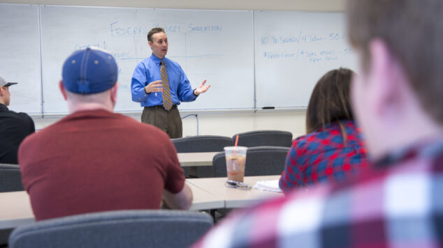 Professor in front of white board addressing a classroom of students